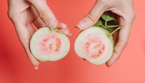 crop woman showing halves of guava